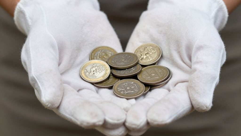 Cotton gloves holding old coins for preservation.